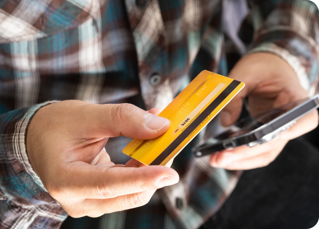 Person holding a credit card and phone.