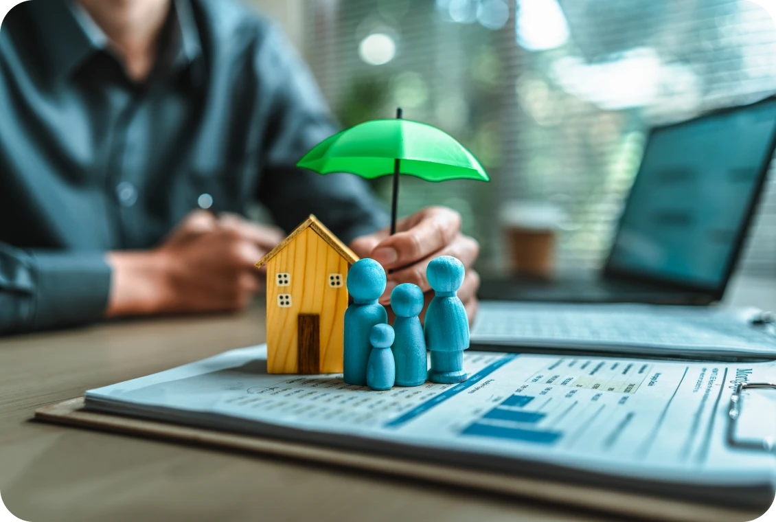 Figures under umbrella next to a house